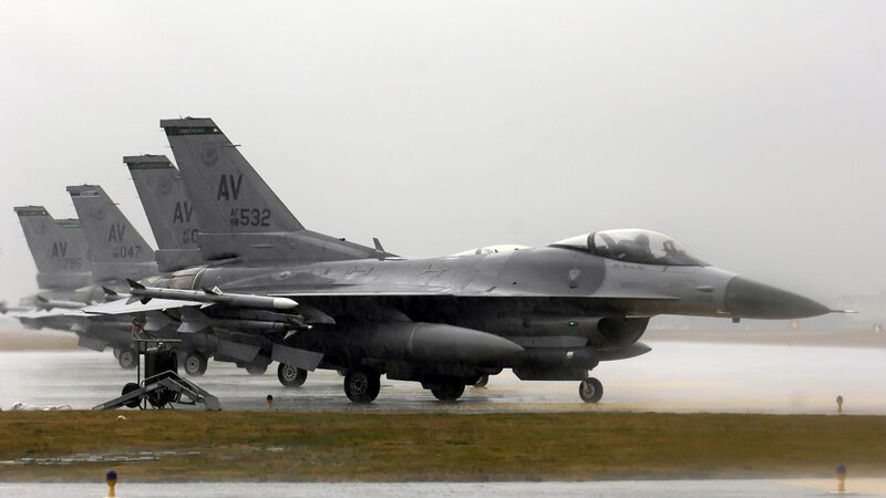 F-16 fighter jets on wet tarmac