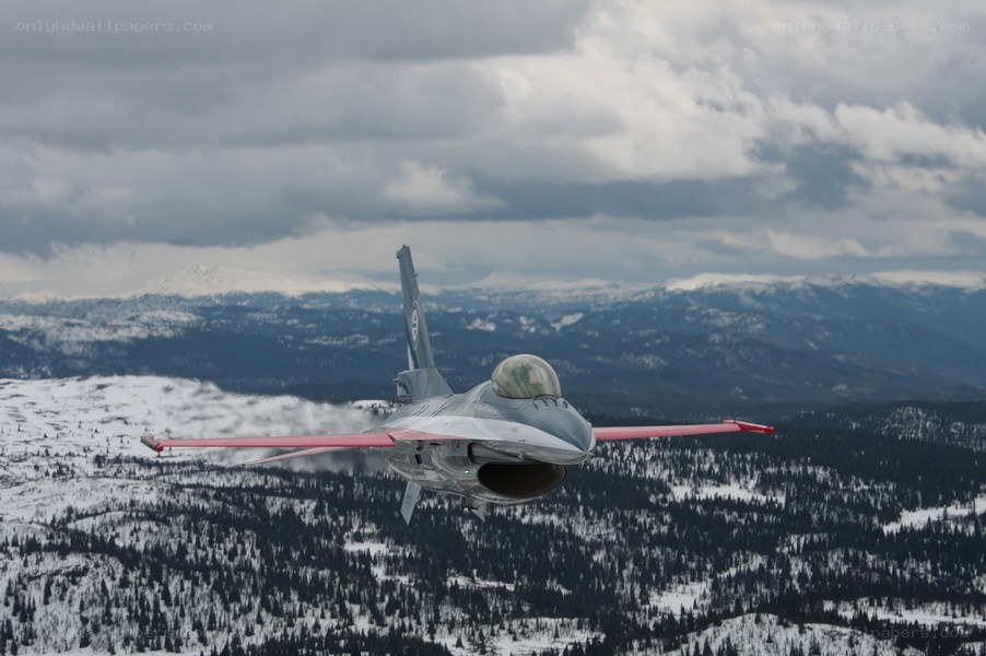 F-16 jet flying over snowy mountains