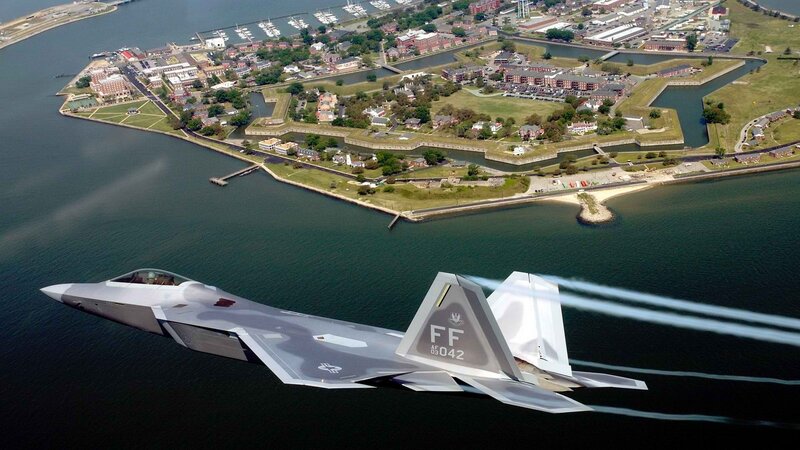 F-22 Raptor flying over a coastal fort