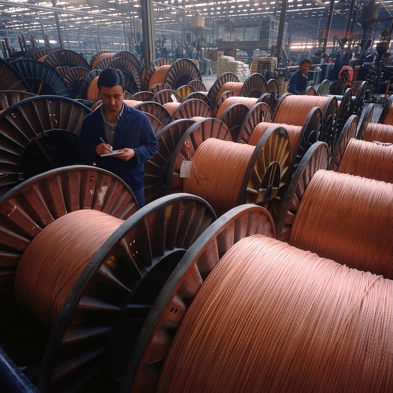 Factory worker with copper wire spools
