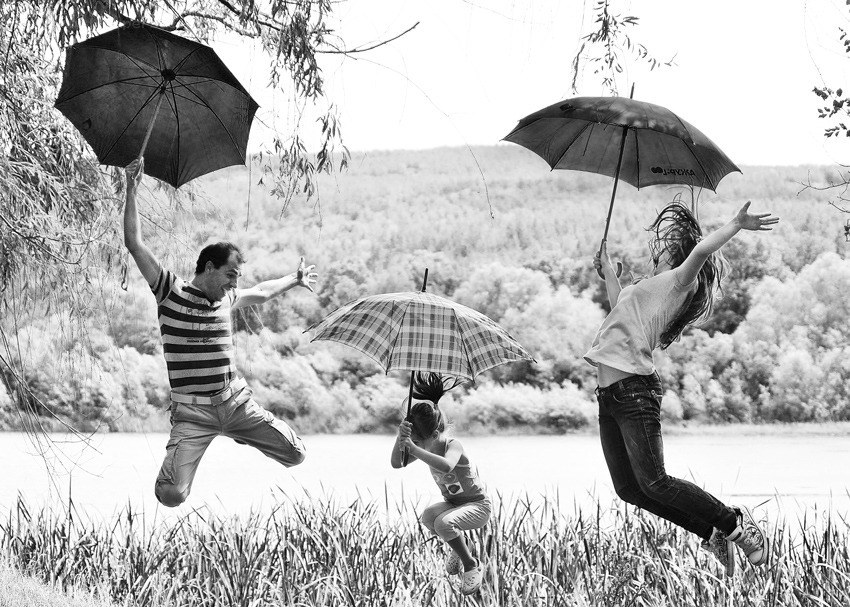 Family jumping with umbrellas