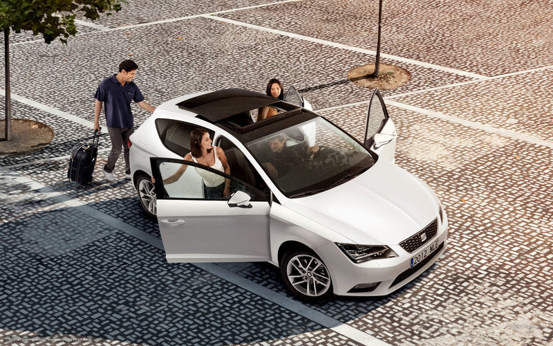 Family loading luggage into white car