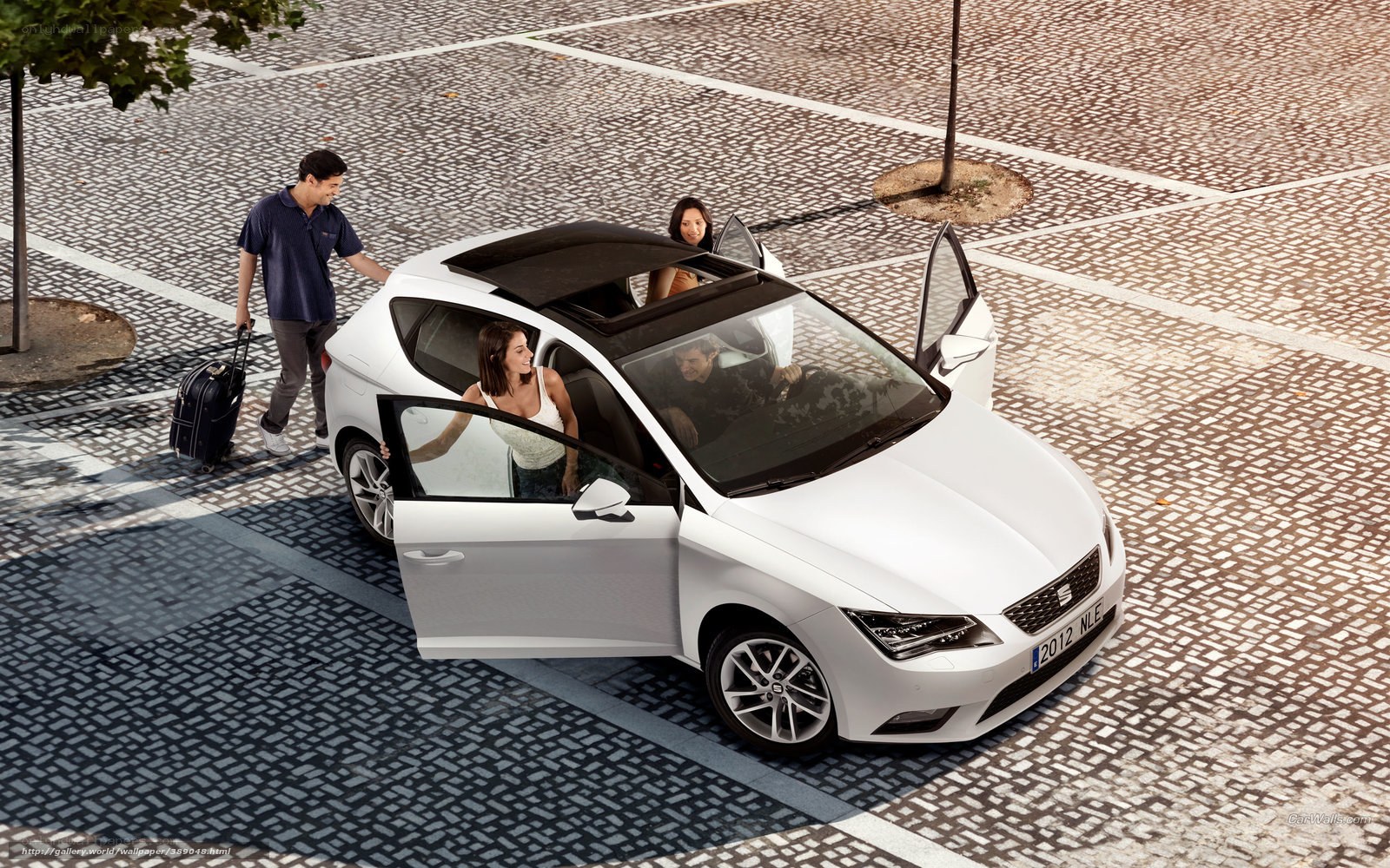 Family loading luggage into white car