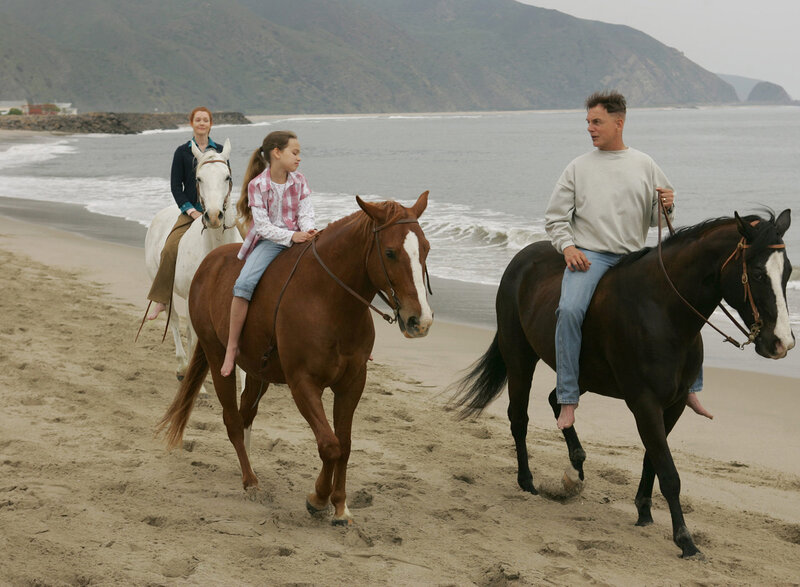 Family riding horses on beach