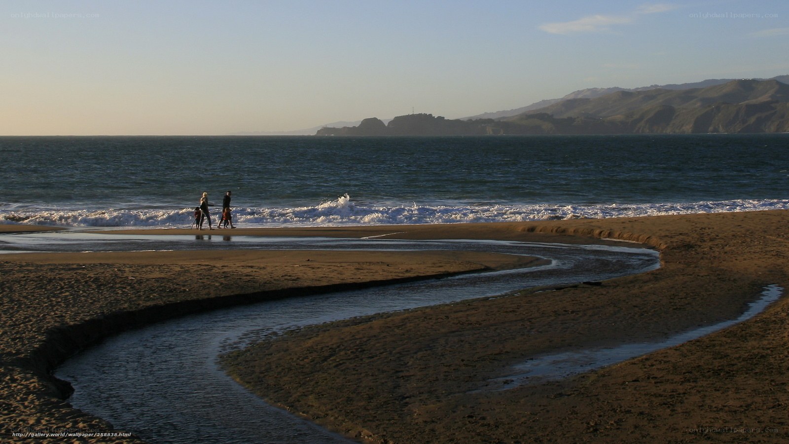 Family walking on beach at sunset
