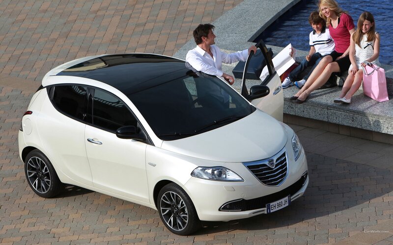 Family with white car by water