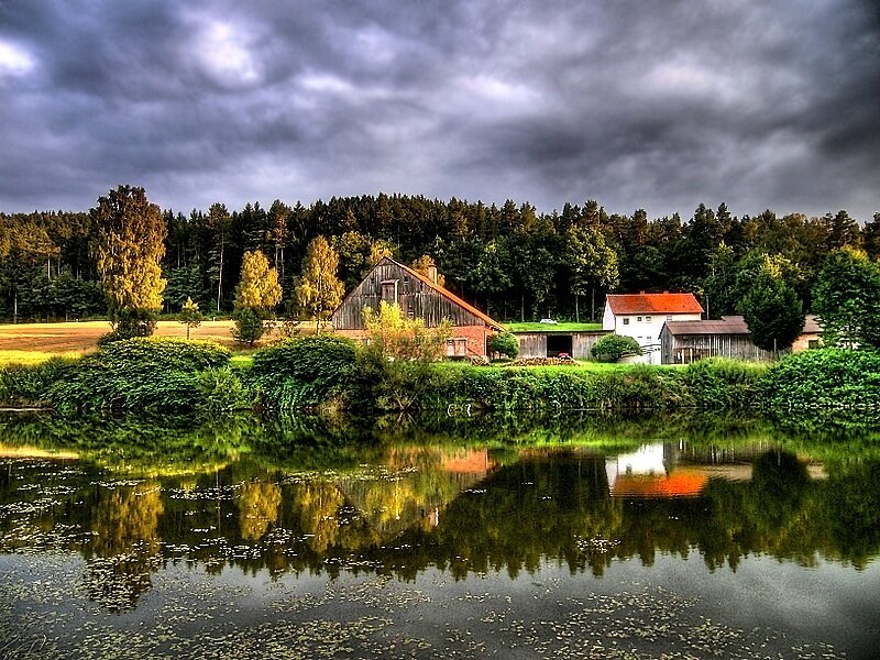 Farm by the lake under stormy sky