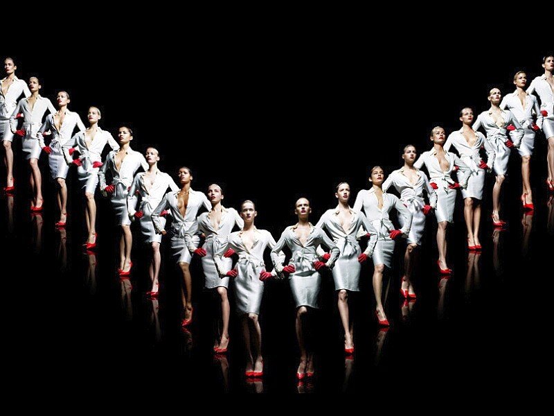Fashion models in white on dark stage