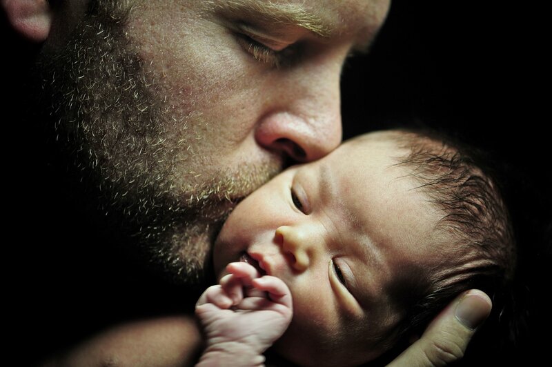 father kissing newborn baby