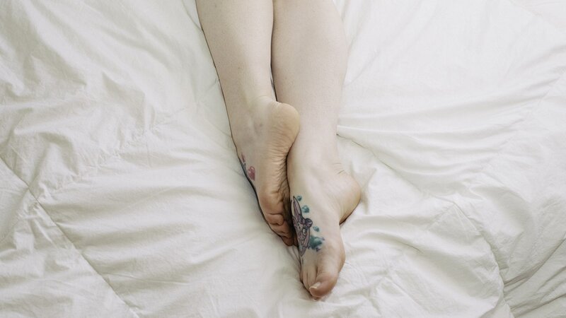 feet with tattoos on bed