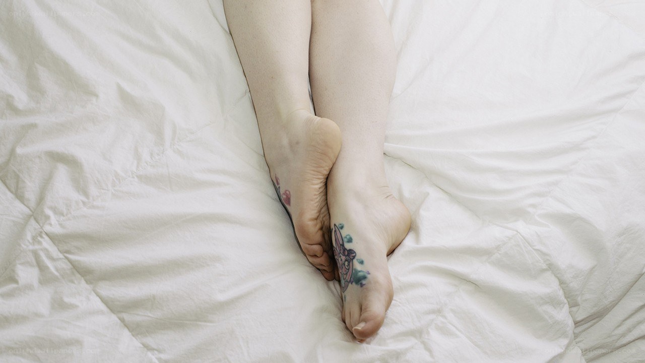 feet with tattoos on bed