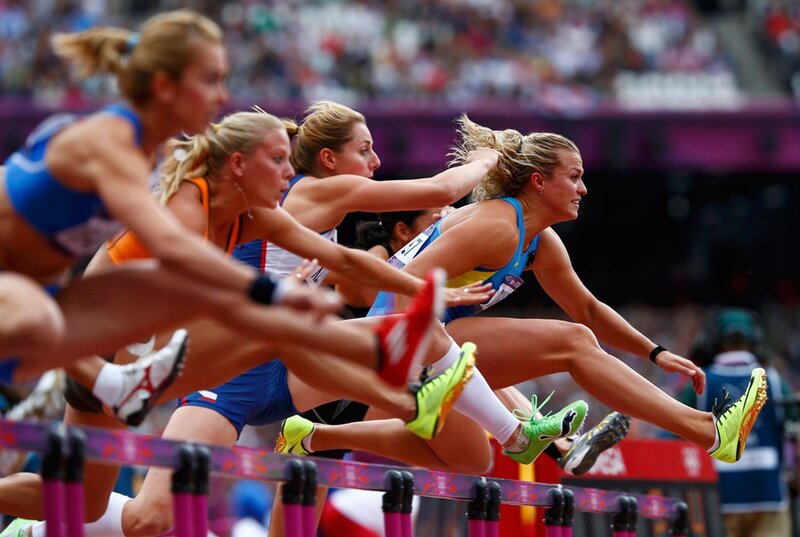Female athletes jumping hurdles