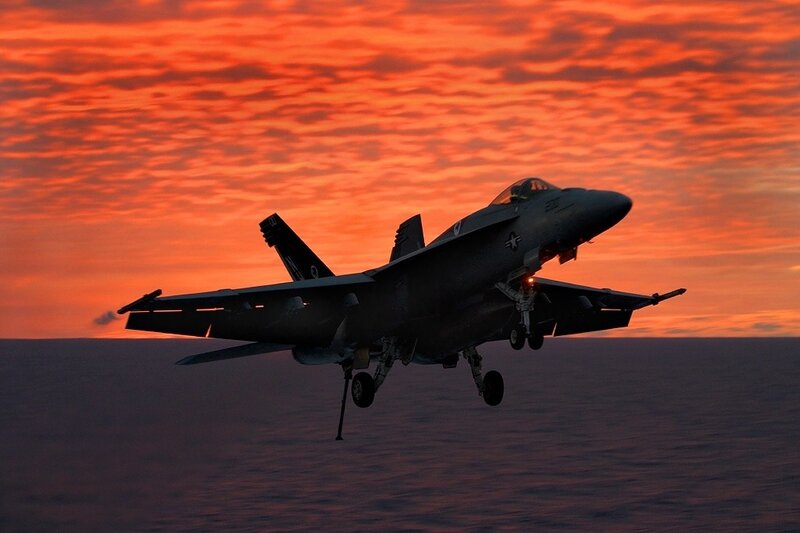 Fighter jet at sunset over ocean