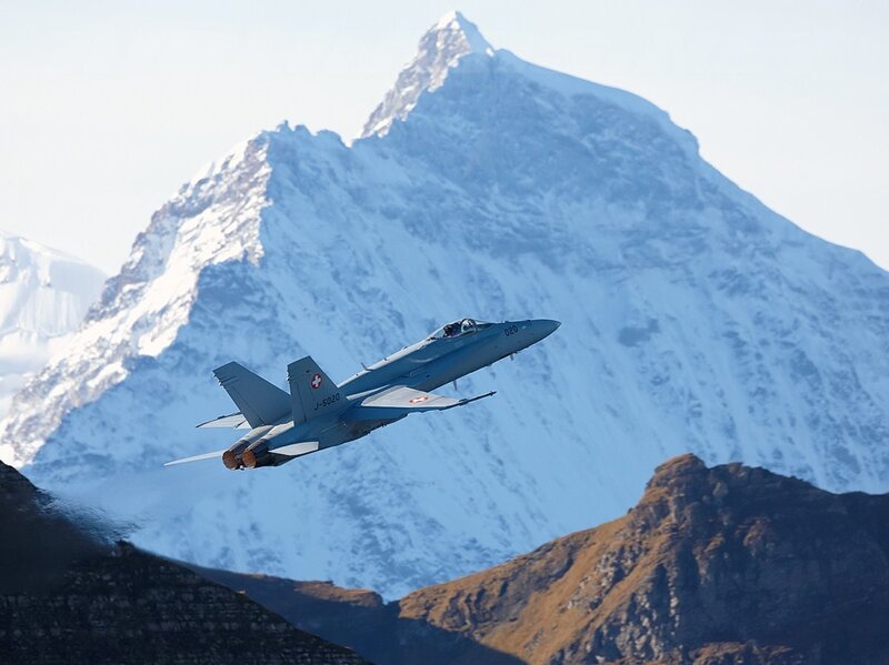 Fighter jet over snowy mountains