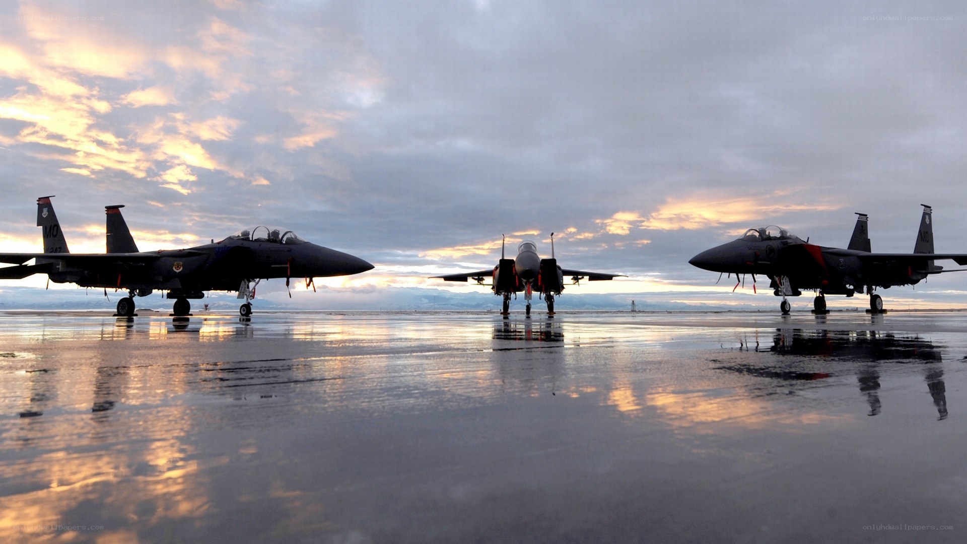 Fighter jets on wet tarmac at sunset