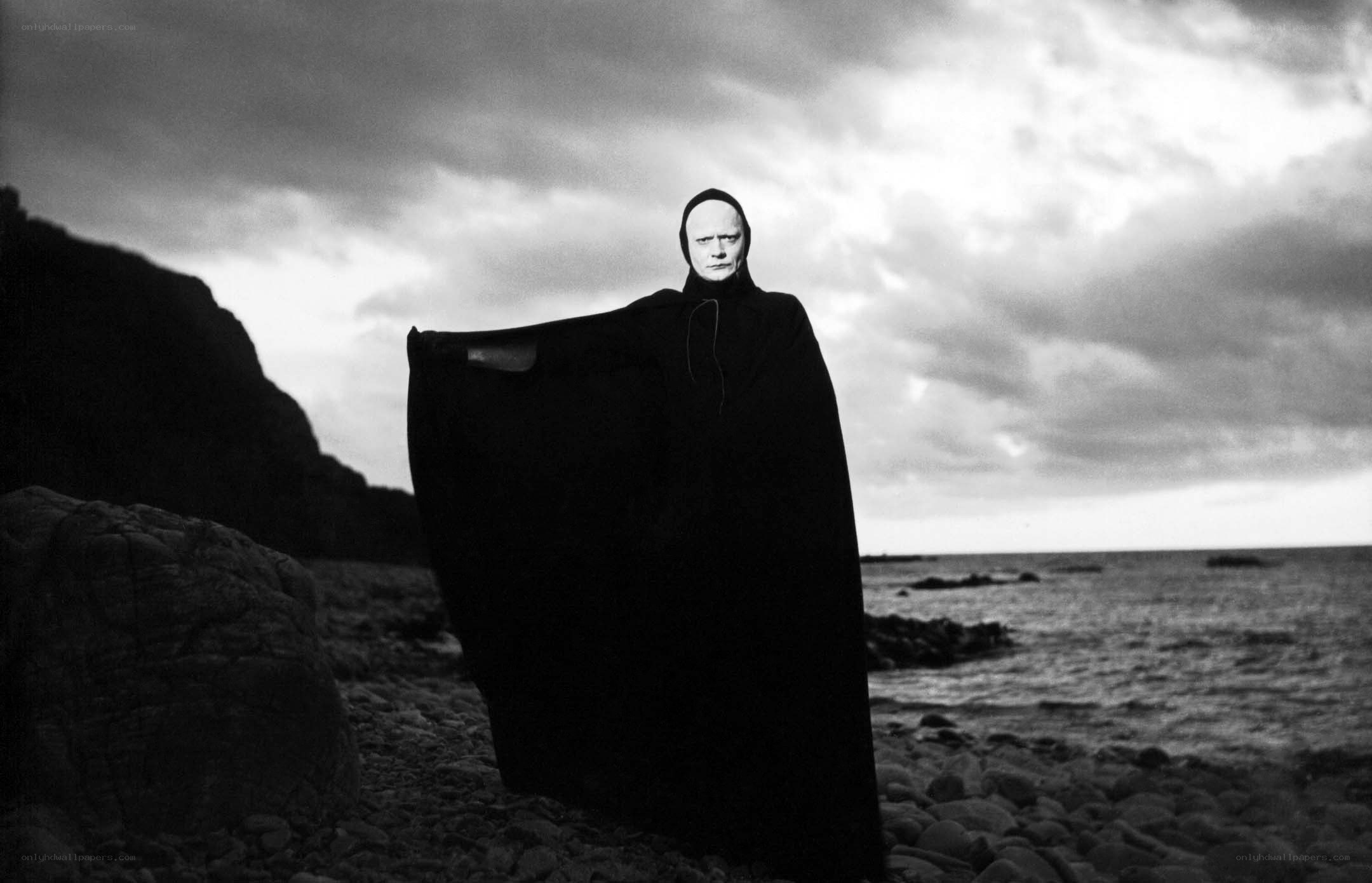 figure in black cloak on beach