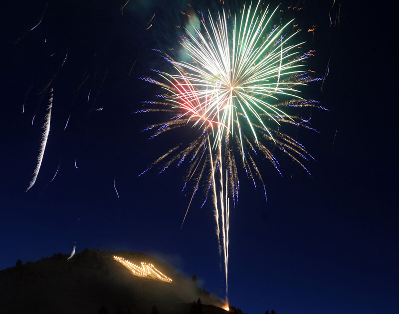 Fireworks over a lit hillside