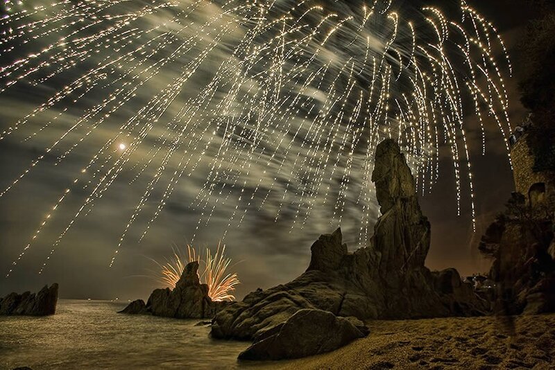 Fireworks over rocky beach