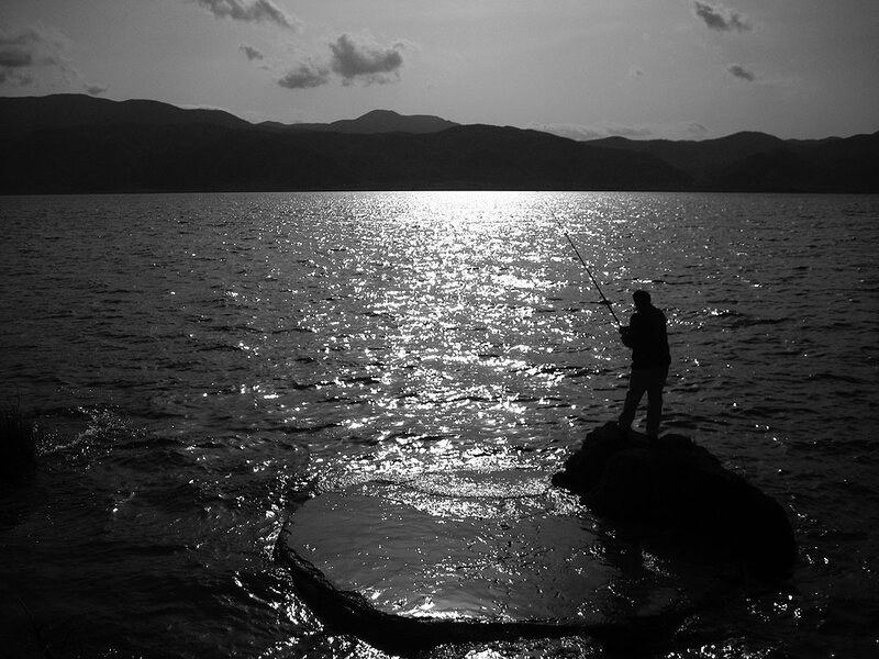 Fisherman at sunset by the lake