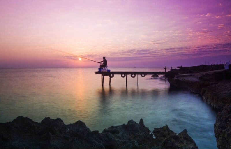 Fisherman at sunset on a pier