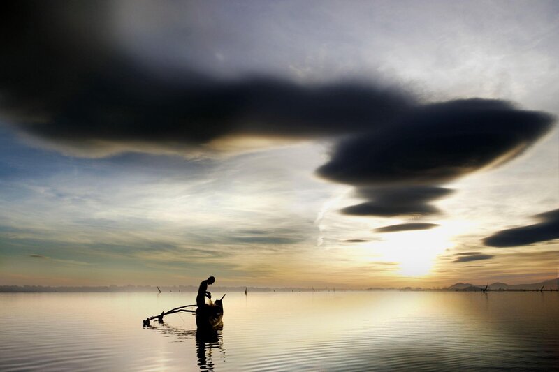 Fisherman at sunset on calm water