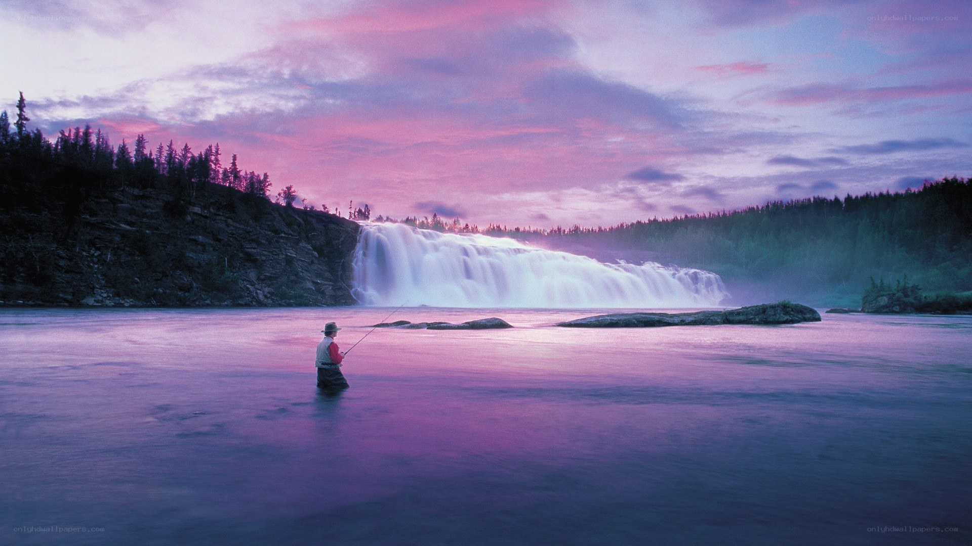 Fisherman at waterfall at dusk