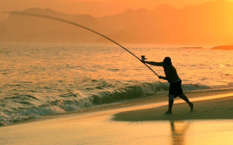 Fisherman casting at sunset