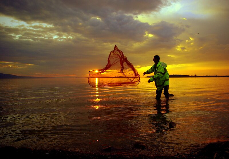 Fisherman casting net at sunset
