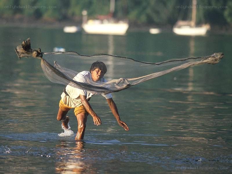Fisherman casting net in water