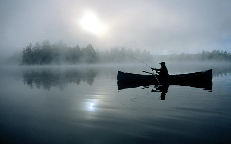 Fisherman in a misty canoe