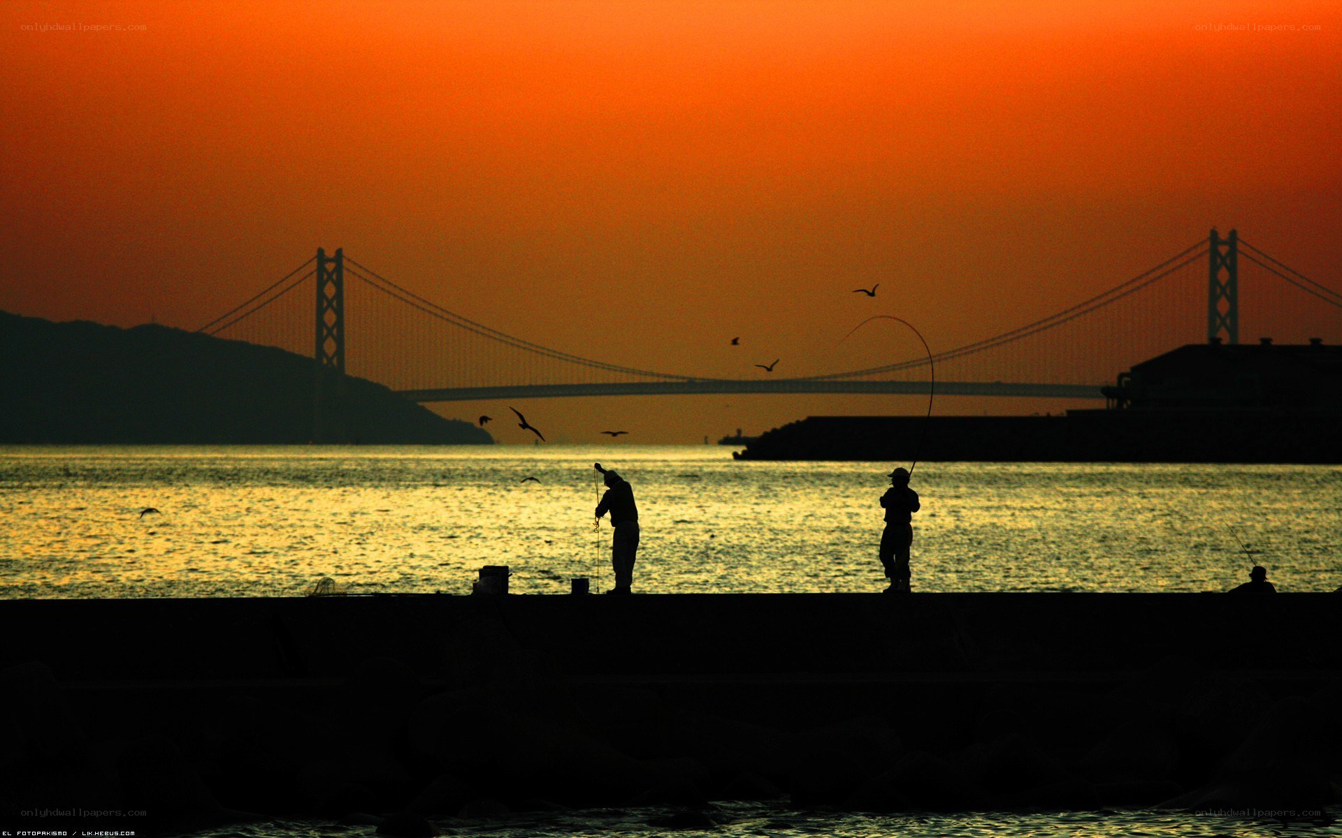 Fishermen at sunset by a bridge