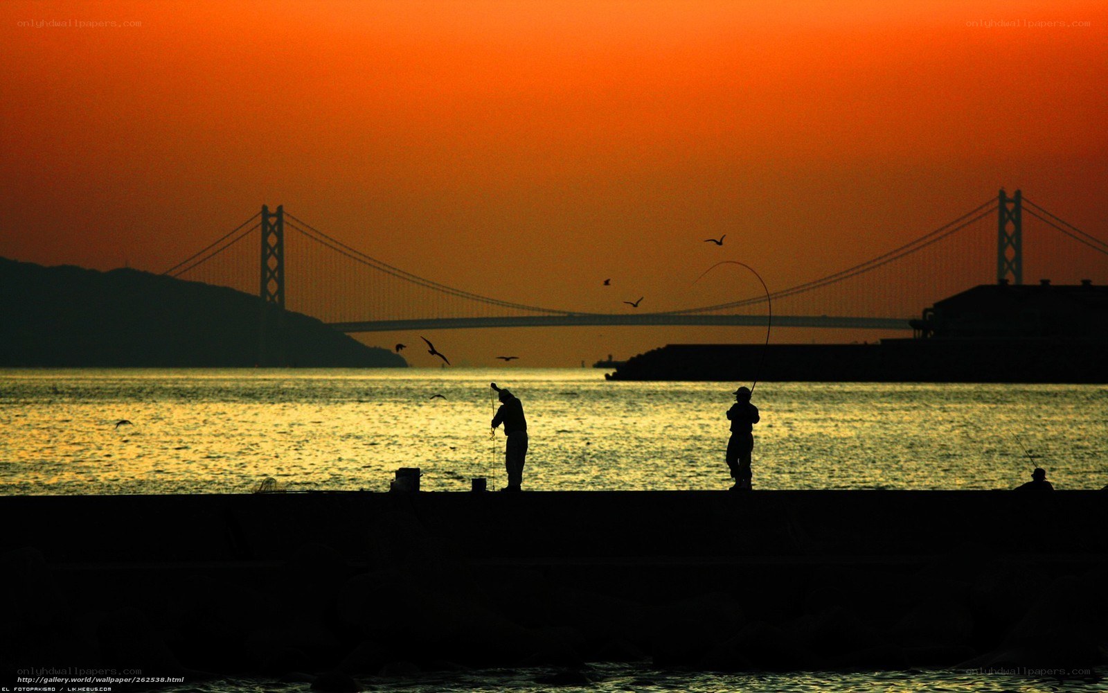 Fishermen at sunset by a bridge