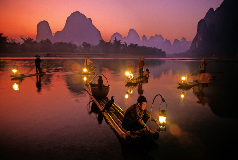 Fishermen on bamboo rafts at dusk