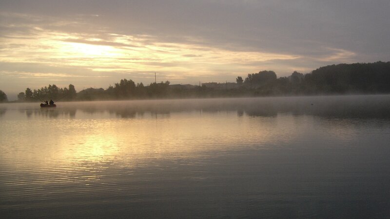 Fishing at dawn on a misty lake