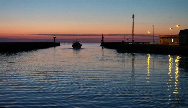Fishing boat entering harbor at dusk