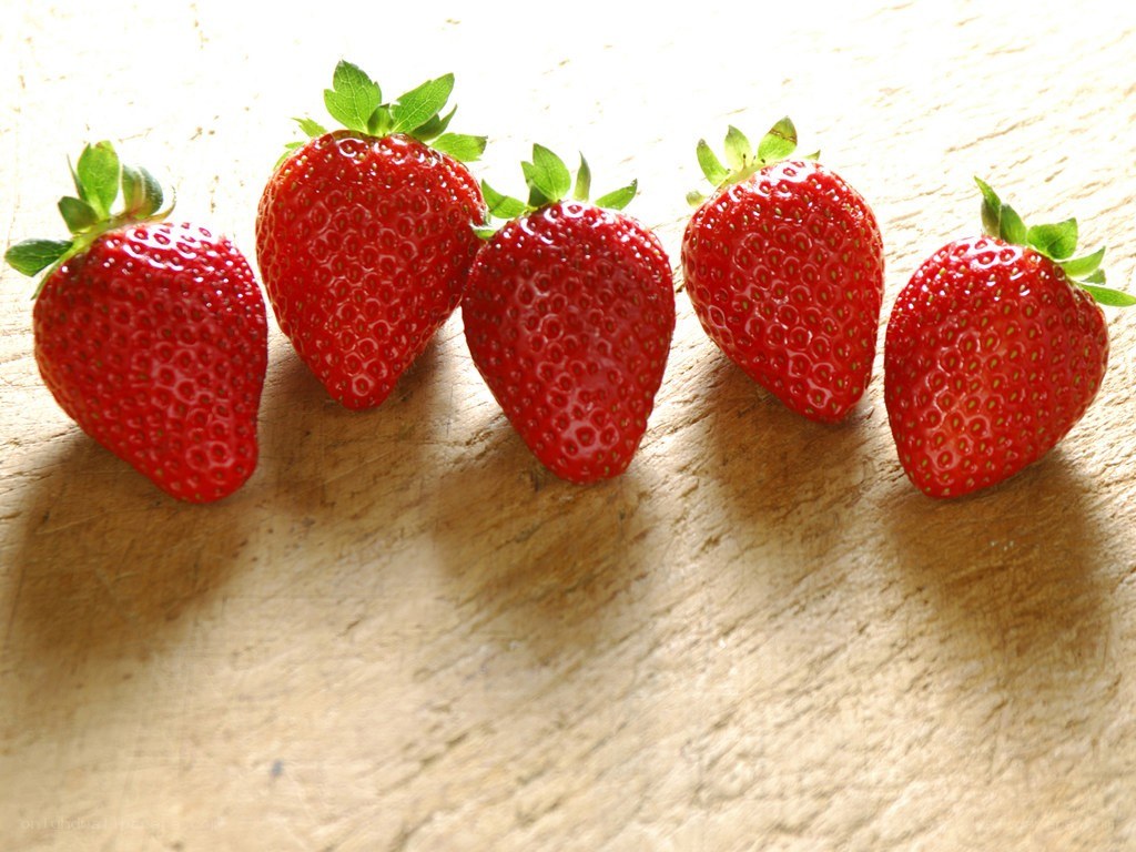 five fresh strawberries in a row