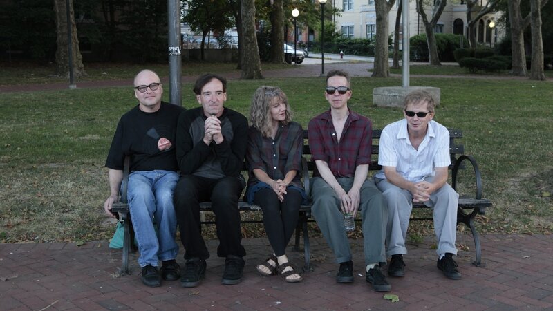five people sitting on a park bench