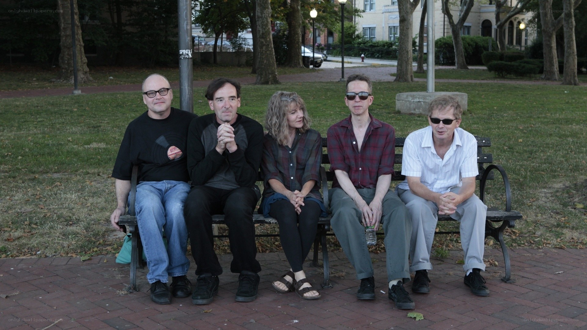 five people sitting on a park bench