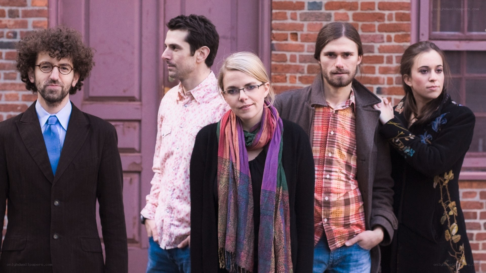 five people standing in front of brick building