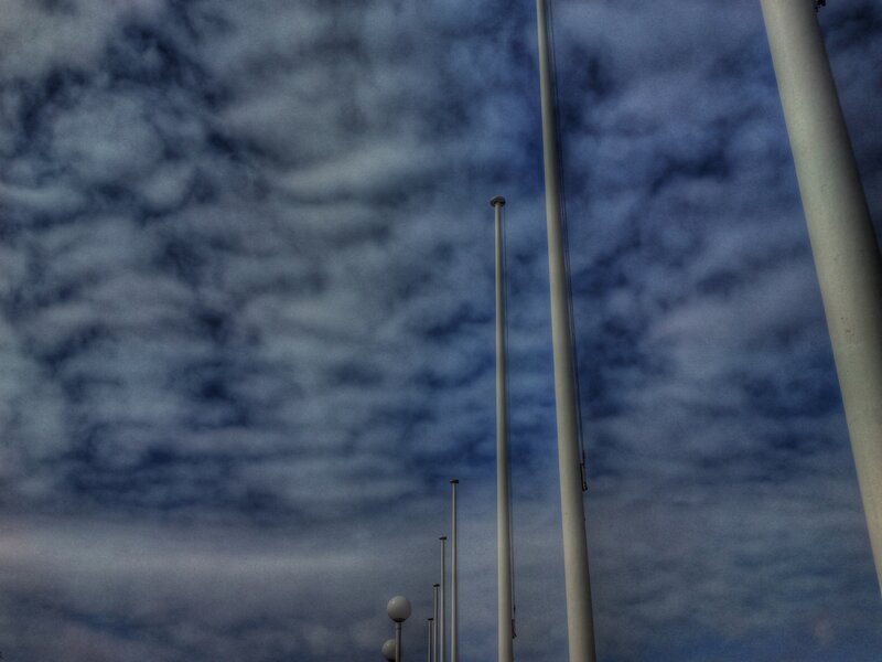 Flagpoles Against Cloudy Sky