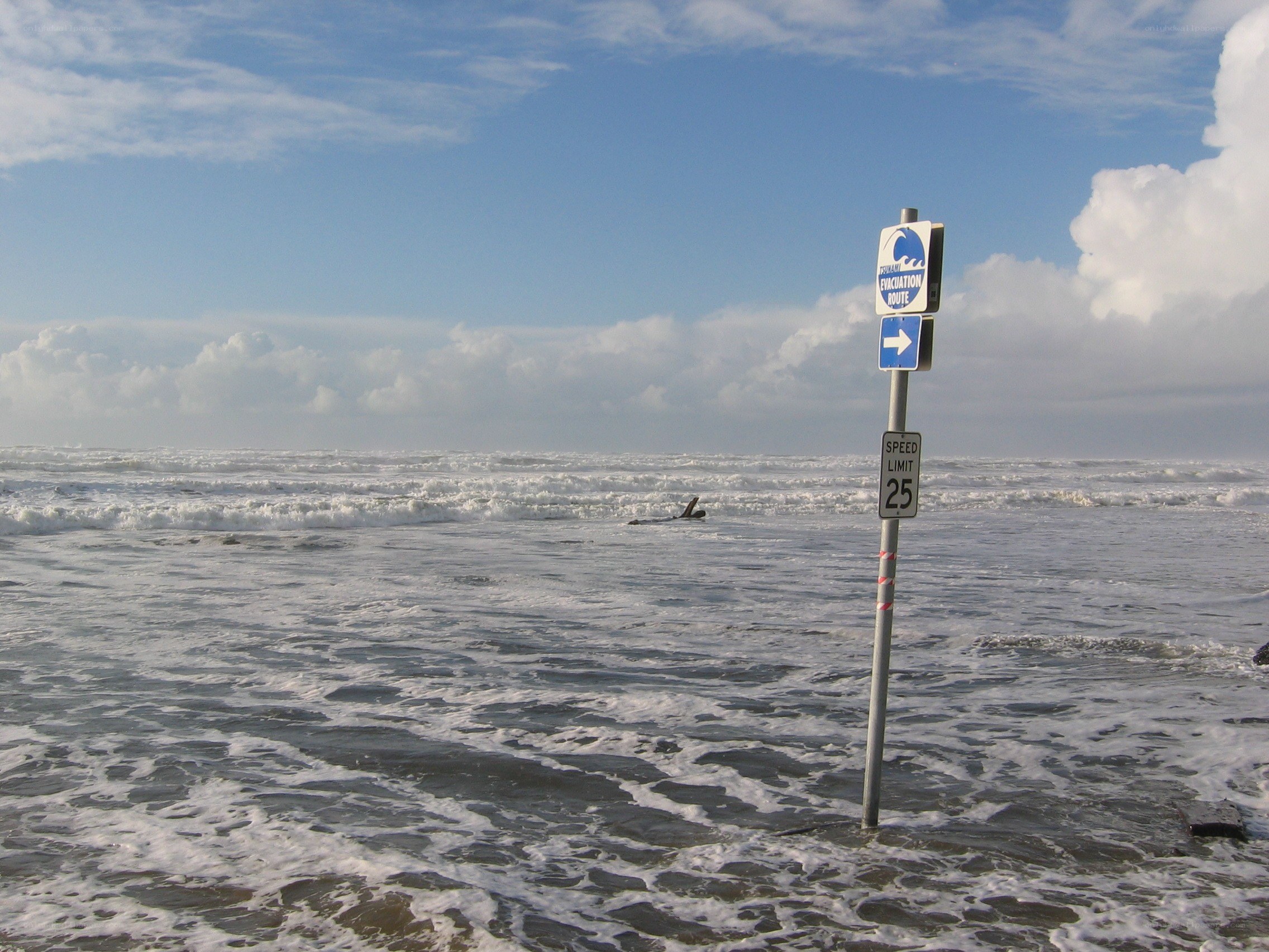 Flooded beach with evacuation sign