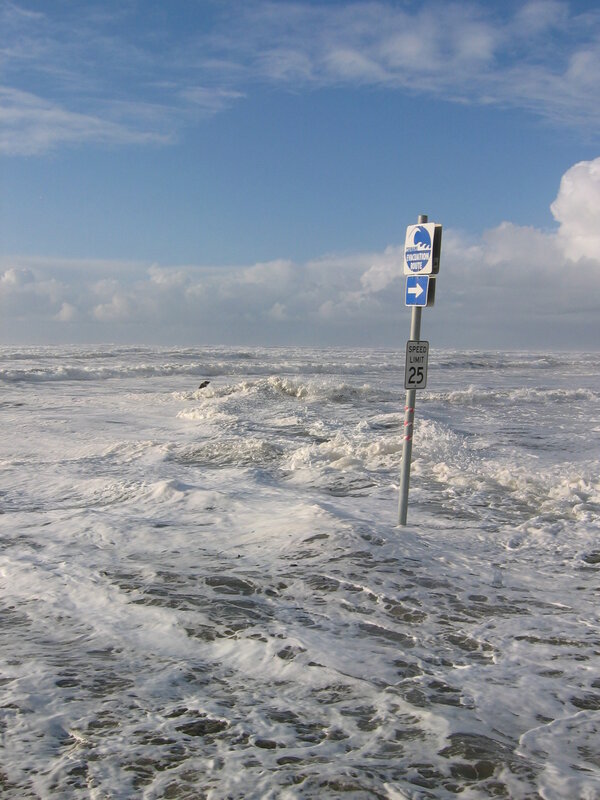 Flooded beach with evacuation sign