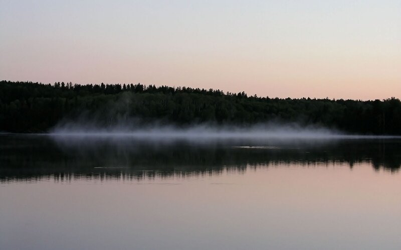 Fog over a calm lake at dawn