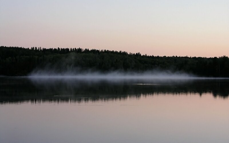 Fog over a calm lake at dawn
