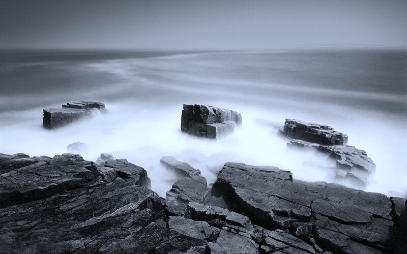 Foggy coastal rocks at sea