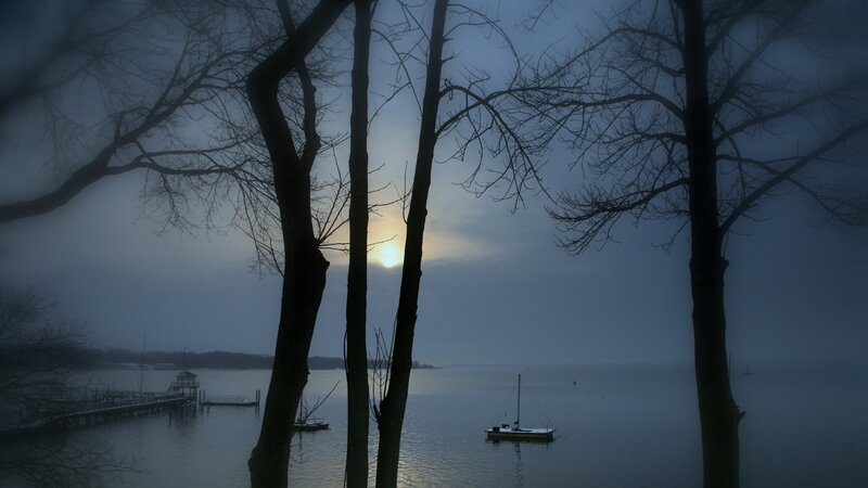 Foggy lake at dawn with boats