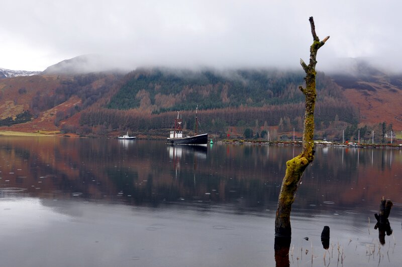 Foggy lake with boats and mountains