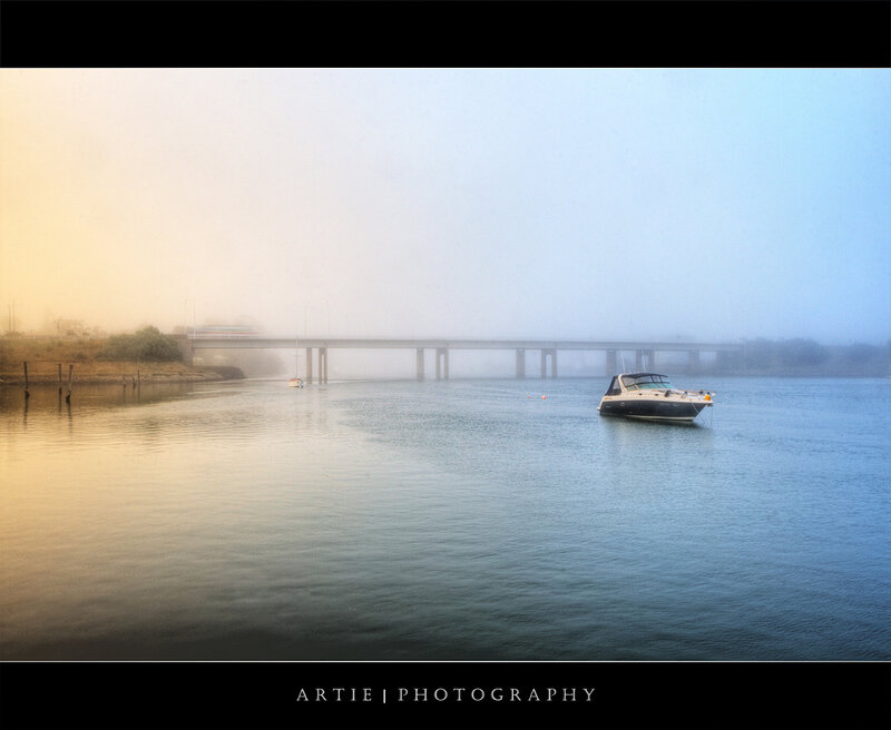 Foggy river with boat and bridge