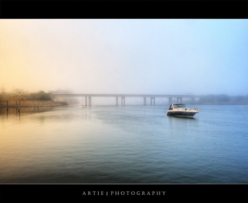 Foggy river with boat and bridge