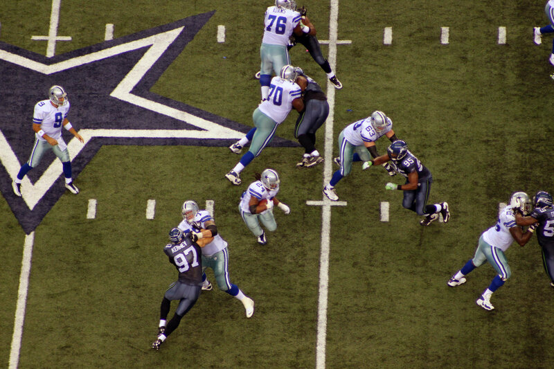 Football Players in Action — Green, Intense, Night, Photograph, Field, Star Logo